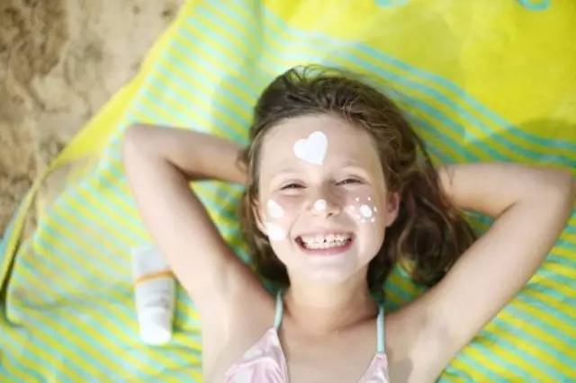 Petite fille avec de la crème solaire sur le visage