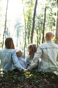 famille de deux adultes et deux enfants portant des veste en jean assorties assis dans la forêt