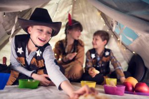 Groupe d'enfants en train de jouer sous un tipi et déguisés en cowboys et indiens