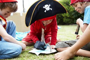 Enfants déguisés en pirates en train de regarder une carte au trésor dans le jardin