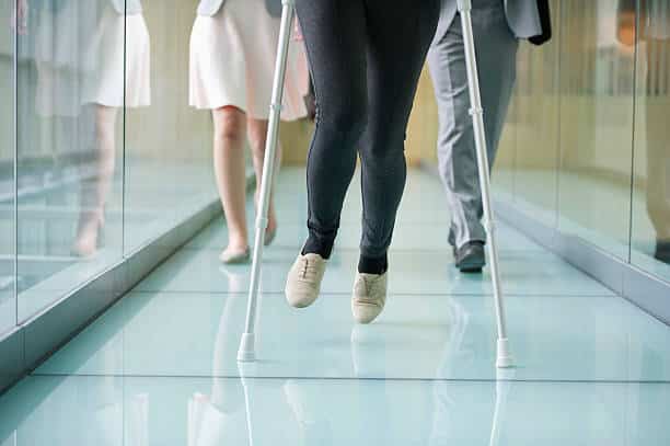 Femme qui marche en béquilles dans un couloir d'hopital