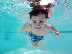 enfant sous l'eau qui sourit dans une piscine