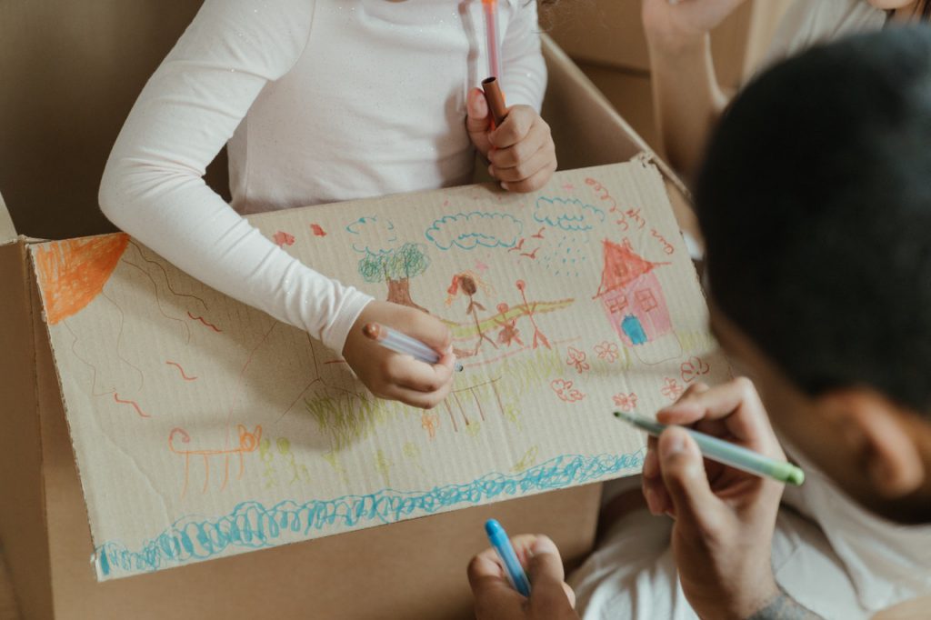 enfant qui dessine sur un carton de déménagement