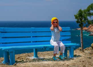 Petite fille assise sur un banc au bord de la mer