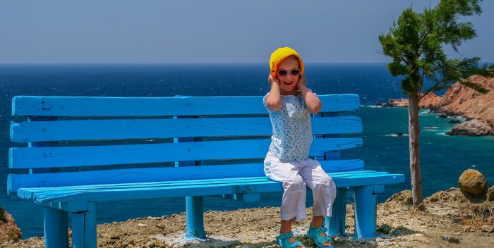 Petite fille assise sur un banc au bord de la mer
