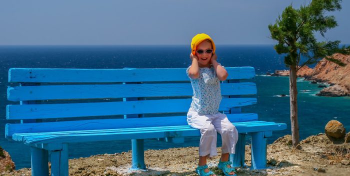 Petite fille assise sur un banc au bord de la mer