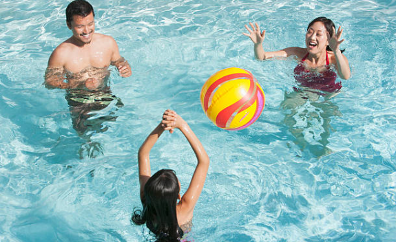 famille qui joue au ballon dans une piscine