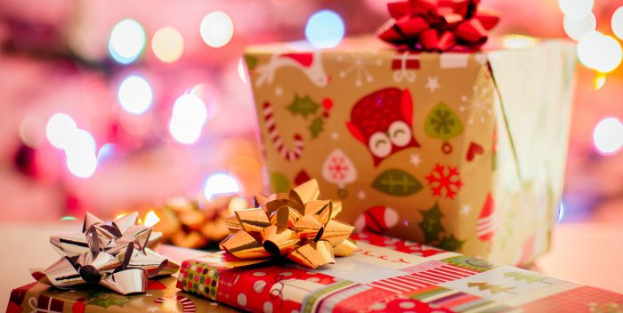 Plusieurs cadeaux de Noël posés sur une table et emballés dans du papier cadeau avec noeud en ruban sur le dessus