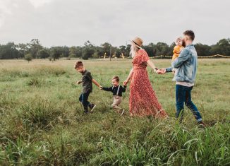 Plusieurs membres d'une famille, parents en enfants, qui courent dans un champ en se tenant par la main