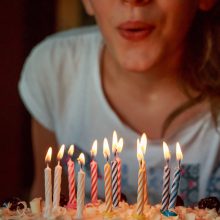 personne qui souffle les bougies sur son gateau d'anniversaire