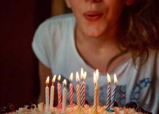 personne qui souffle les bougies sur son gateau d'anniversaire