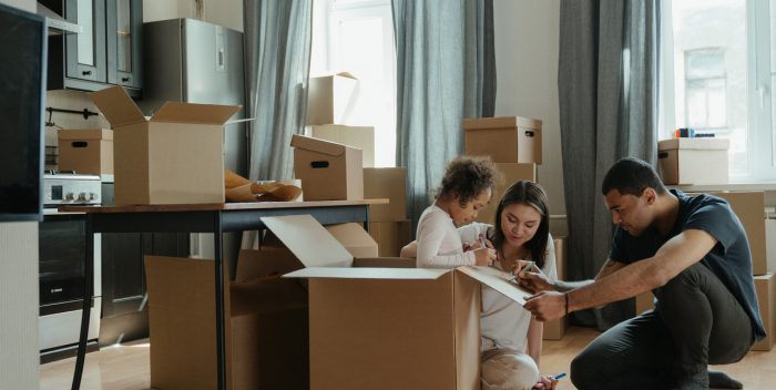 enfant assise dans un carton et qui dessine dessus avec ses parents